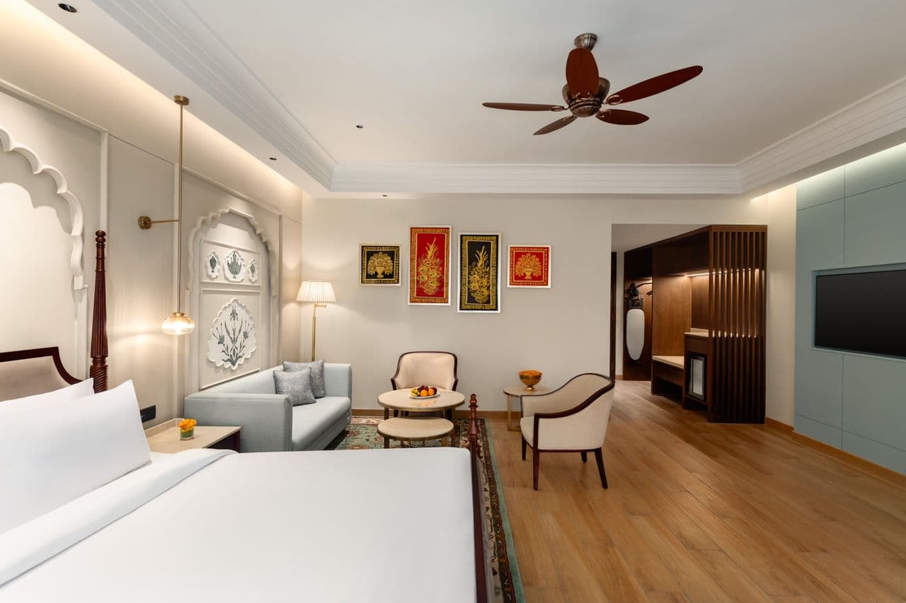 A guest room with a large bed, sofa seating and a television